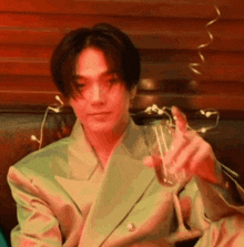 a young man in a suit is holding a glass of wine .