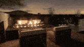 a patio area with a fireplace and chairs at night