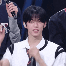 a young man in a white shirt and tie is holding a microphone in his hand