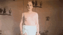 a bald man is standing in a room with a diaper on his waist .