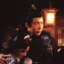 a man and a woman are hugging each other in front of a lantern in a dark room .