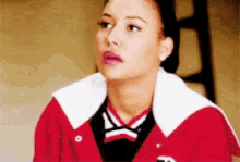 a woman in a red jacket with a white collar is looking at the camera .