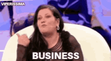 a woman is sitting in a chair and giving a thumbs up and says business .