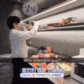 a man in a white sweater is standing in a kitchen with a sign that says " who hired this guy "