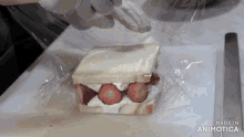 a sandwich with strawberries and whipped cream is wrapped in plastic wrap and made in animatica