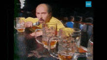 a man is singing into a microphone while sitting at a table with beer mugs