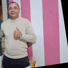 a man is giving a thumbs up in front of a pink and white wall