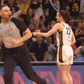 a female basketball player with the number 22 on her jersey is talking to a referee