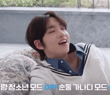 a young man is laying on a couch with his eyes closed and a foreign language behind him