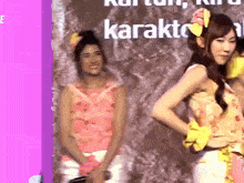 two girls are standing in front of a sign that says karakto on it