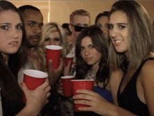 a group of people are holding red cups and one woman is making a funny face