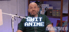 a man in a green shirt is sitting in front of a microphone with the words shit anime on the screen behind him