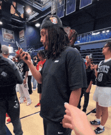 a man wearing a boston celtics shirt stands in a gym