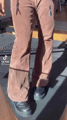a person wearing brown pants and black shoes with a tiktok watermark