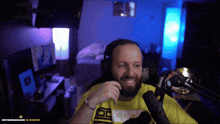 a man wearing headphones and a yellow shirt is smiling in front of a microphone that says 10 months on the bottom