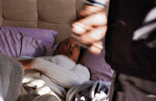 a person is laying on a bed with purple pillows