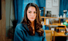a woman in a blue sweater looks at the camera