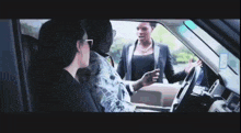 a woman sitting in a car talking to a man