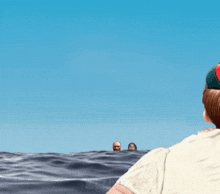 a man in a baseball cap is looking at two men in the ocean