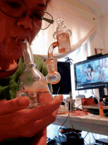 a woman wearing glasses is smoking from a glass pipe
