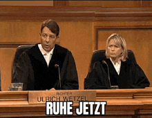 a man and a woman are sitting at a judge 's bench .