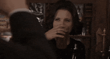 a woman in a black dress is drinking a beer