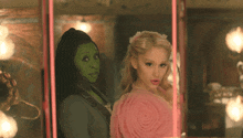 a woman in a green mask and a woman in a pink dress pose for a picture