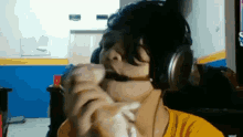 a boy wearing headphones and a microphone is eating a sandwich .