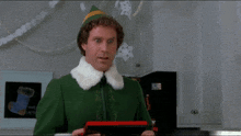 a man in a green elf costume is holding a picture frame in his hands .