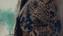 a close up of a woman wearing a leopard print shirt and a leopard print scarf .