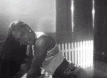 a black and white photo of a woman dancing in front of a white fence .