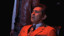 a man in a suit and tie says magnificent in a dark room