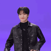 a young man wearing a black leather jacket and a black turtleneck is making a funny face