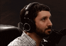 a man wearing headphones is sitting in front of a microphone .