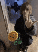 a young man is holding a stuffed flower and giving the middle finger .
