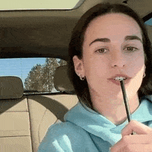 a woman is sitting in the back seat of a car holding a pen in her mouth .