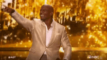 a man in a suit is standing on a stage with his arms outstretched