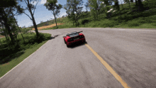 a red sports car is driving down a road with trees in the background