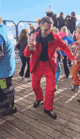 a man in a red jacket holds a glass of beer