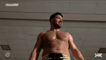 a shirtless wrestler is standing in front of a wall with #revolverfriday written on it