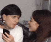 a man and a woman are looking at each other while the woman holds a cell phone .