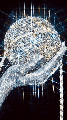 a statue of a hand holding a sphere covered in diamonds