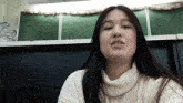 a woman with long hair wearing a white turtleneck sweater