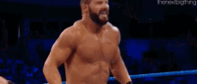 a man without a shirt is standing in a wrestling ring with a referee .