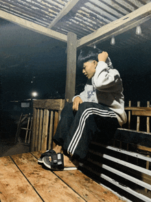 a person sitting on a wooden bench wearing a hoodie that says ' a ' on it