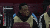 a man sits in a soccer stadium with a scoreboard behind him that says champions league