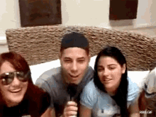 a group of people are sitting on a couch and one of them is holding a microphone ..