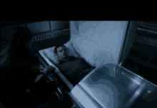 a man laying in a coffin with a woman standing next to him