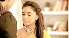 a woman wearing a necklace and earrings is looking at a man .