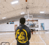 a man stands on a basketball court wearing a hoodie with flames on it and the number 71 on the back